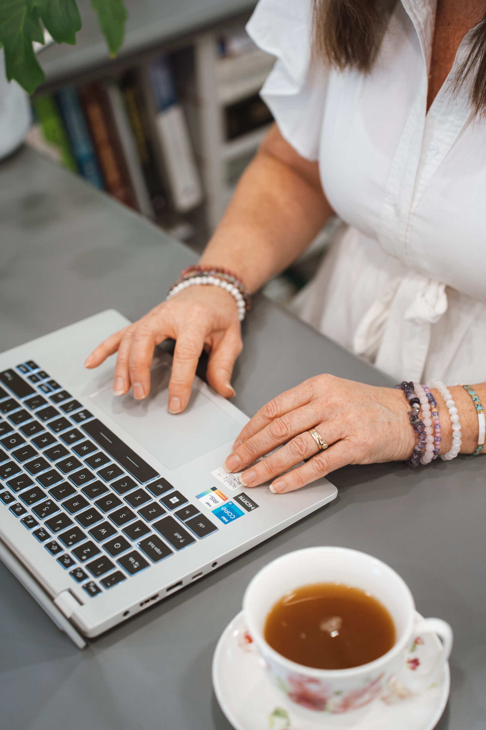 Naturopath Louise Mace preparing personalised health plans on her laptop with a calming tea.